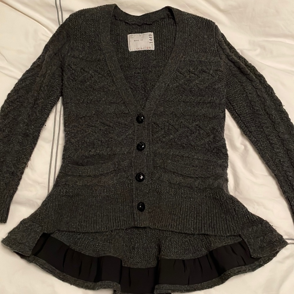 Sacai wool v-neck peplum sweater with ribbon detail and front pockets.